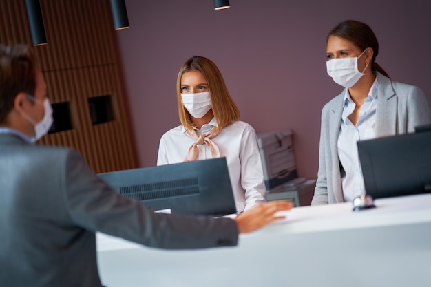 empresário mascarado na recepção de um hotel fazendo check-in