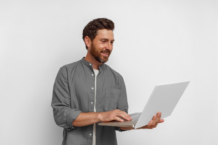Foto empresário masculino sorridente trabalhando no laptop em pé no fundo branco