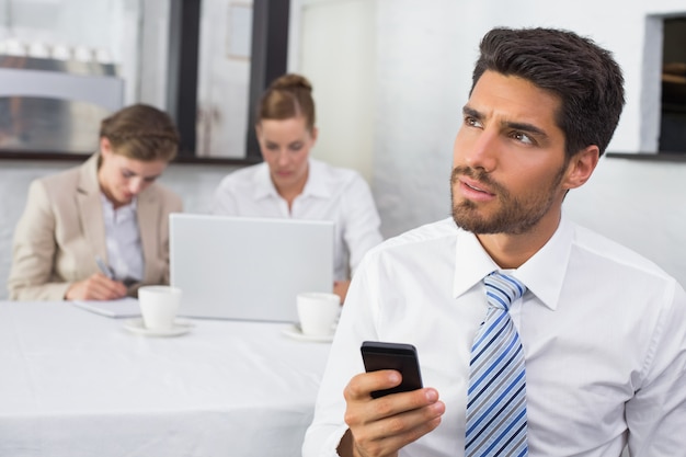 Empresário mensagens de texto com os colegas na mesa de escritório