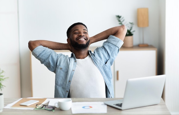 Empresário milenar sorridente descansando no local de trabalho contemporâneo