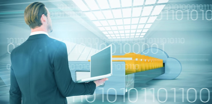 Foto empresario mirando hacia arriba sosteniendo el portátil contra la imagen compuesta del cajón de cloud computing