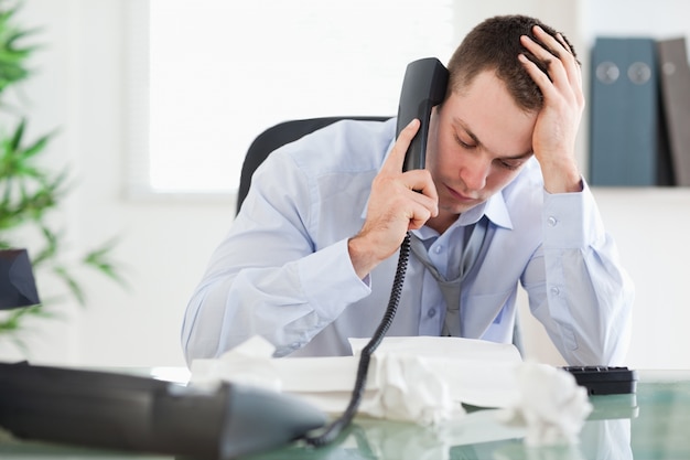 Empresario mirando una factura mientras habla por teléfono