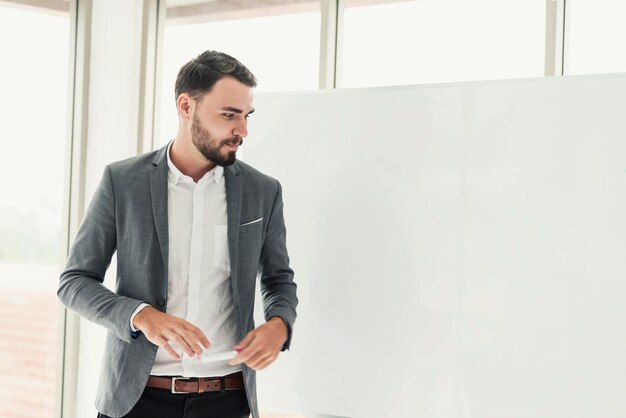 Empresario mirando hacia otro lado mientras está de pie junto a la pizarra en la oficina