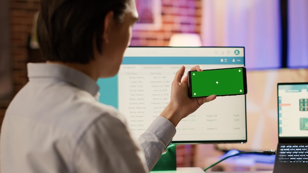 Empresario mirando la pantalla verde horizontal en el teléfono inteligente, usando una clave de croma en blanco con una plantilla de espacio de copia de maqueta y un fondo aislado. Aplicación de teléfono móvil en pantalla.