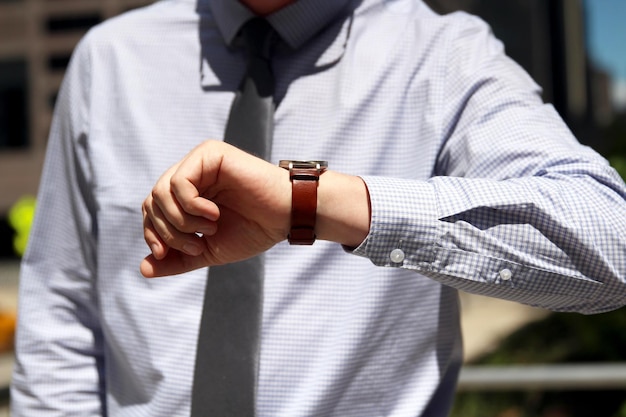 Foto empresario mirando su reloj camino a la oficina concepto de estilo de vida empresarial