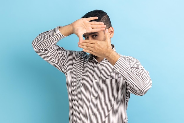 Empresario mirando a través de la imagen de recorte del gesto del marco de la mano haciendo zoom y centrándose en la distancia