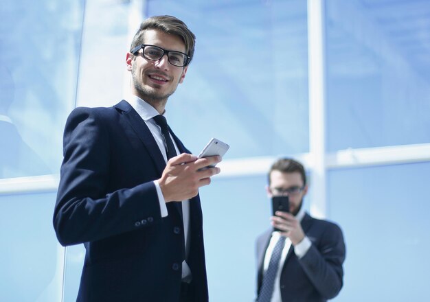 Empresário moderno com um smartphone no escritório de fundophoto com espaço de cópia