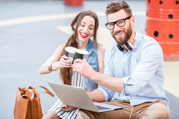 Empresario moderno y empresaria trabajando con laptop y café al aire libre en el suelo del helipuerto. Concepto de negocio de estilo de vida