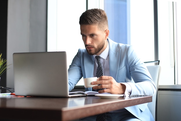 Empresário moderno pensando em algo enquanto está sentado no escritório.