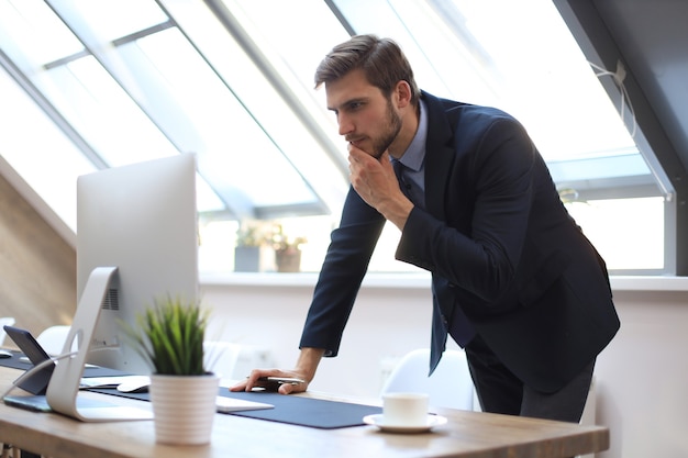 Empresário moderno pensando em algo enquanto está sentado no escritório.