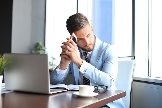 Empresário moderno pensando em algo enquanto está sentado no escritório.