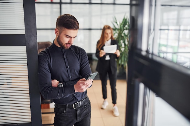 Foto empresario moderno de pie en el interior de la oficina. su colega detrás.