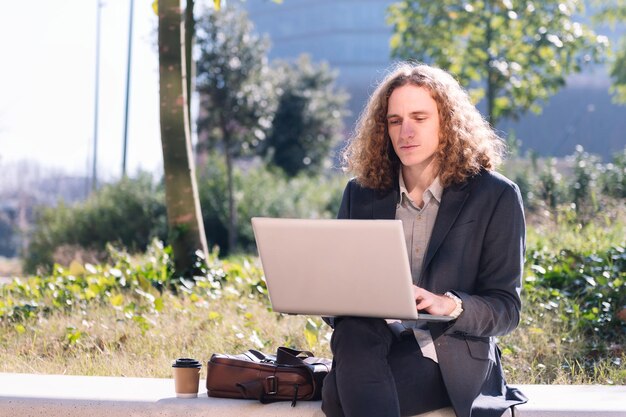 Empresário moderno trabalhando ao ar livre com um laptop