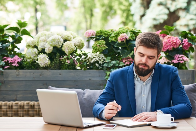 Empresário moderno trabalhando no café ao ar livre