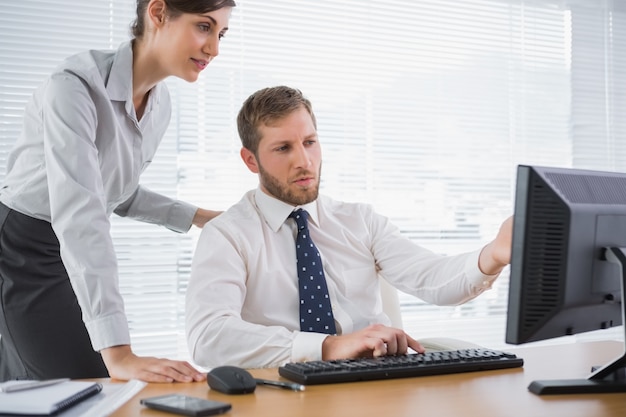 Empresário mostrando a seu colega algo no computador