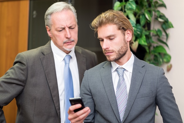 Empresario mostrando su teléfono móvil a un colega