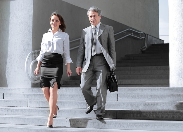 Empresario y mujer de negocios caminando por las escaleras abiertas del edificio de oficinas.Foto con espacio de copia