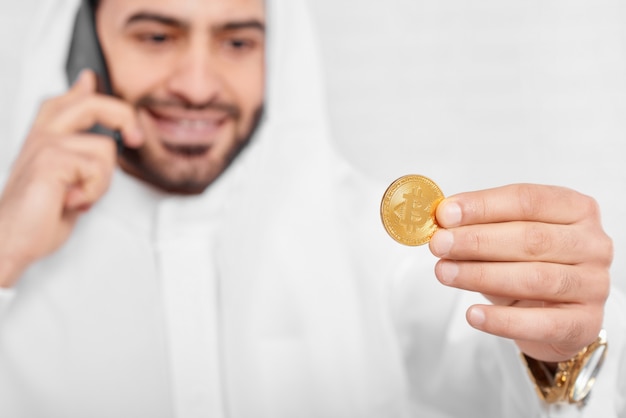 Un empresario musulmán mira bitcoin dorado