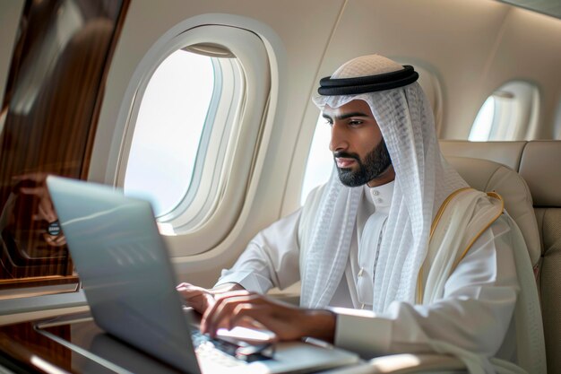 Empresario musulmán con vestimenta tradicional trabajando en una computadora portátil a bordo durante un viaje de negocios