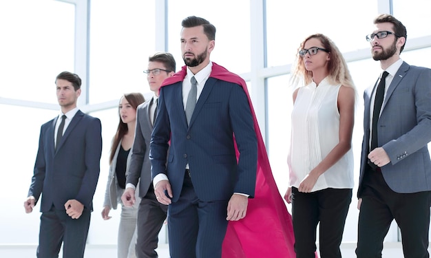 Empresário na capa do Superman e equipe de negócios em pé no saguão do escritório