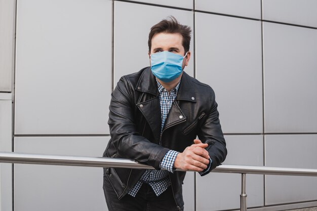 Empresário na máscara em um fundo de prédio fechado, coronavírus, doença, infecção, quarentena, máscara médica