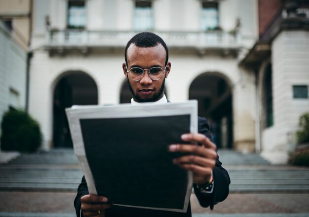 El empresario negro lee el periódico sobre las finanzas de la ciudad