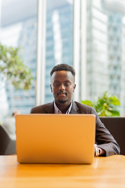 Empresario negro usando computadora portátil en la cafetería