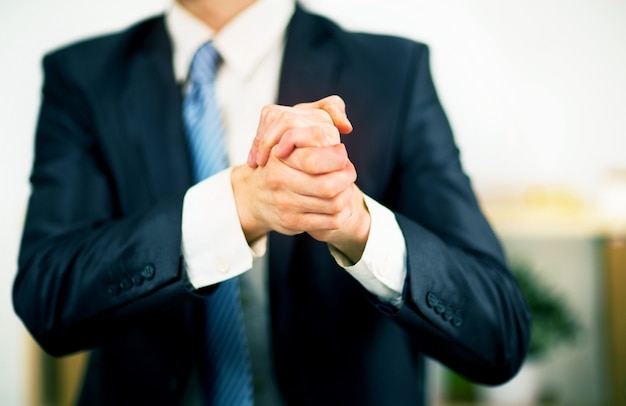Empresário no escritório com as mãos postas. vontade de amizade e cooperação.