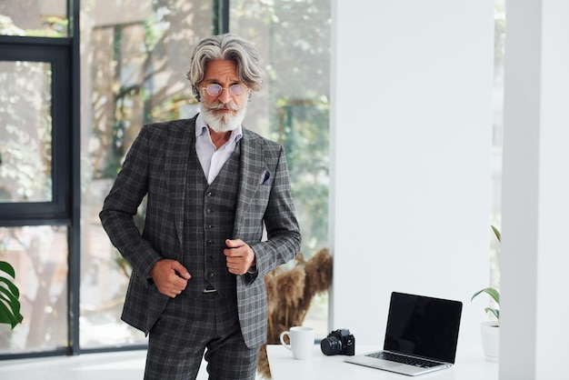 Empresário no escritório homem moderno elegante sênior com cabelos grisalhos e barba dentro de casa