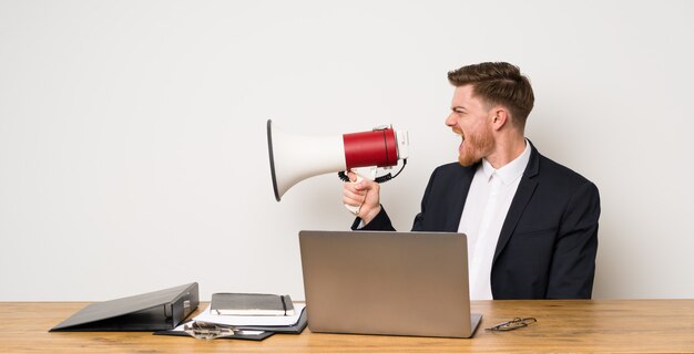 Empresario en una oficina gritando a través de un megáfono