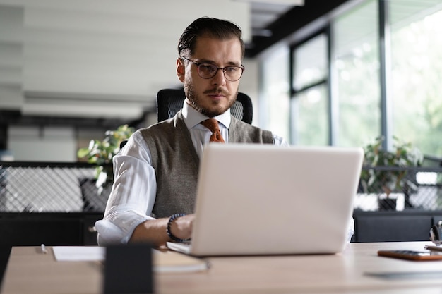 Empresario de oficina moderna que trabaja en la computadora Retrato de un exitoso ingeniero de software de TI de mediana edad que trabaja en una computadora portátil