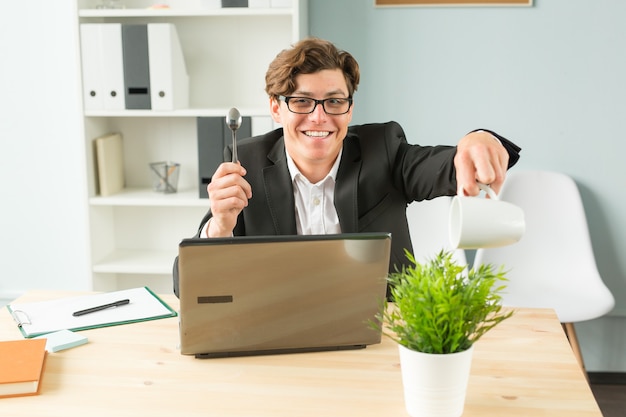 Empresario en la oficina regando una planta