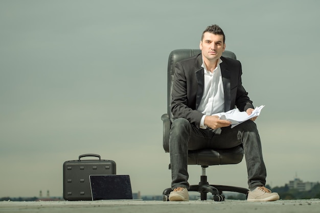 Empresario con papel en la oficina al aire libre