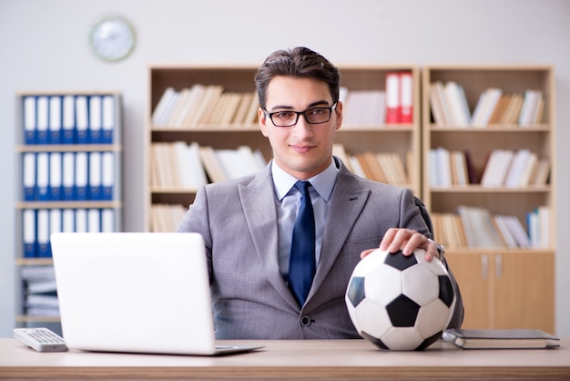 Empresario con pelota de futbol en la oficina