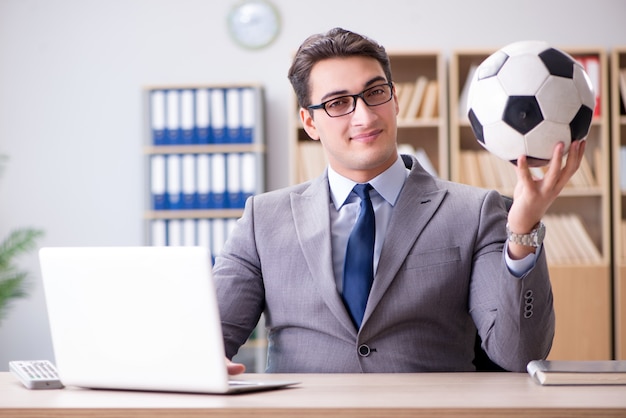 Empresario con pelota de futbol en la oficina