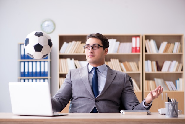 Empresario con pelota de futbol en la oficina