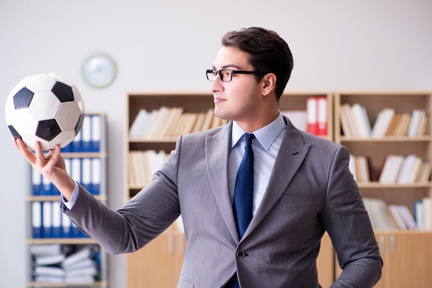 Foto empresario con pelota de futbol en la oficina