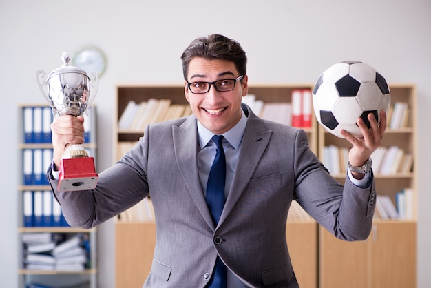 Empresario con pelota de futbol en la oficina