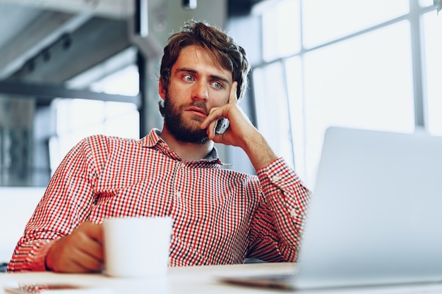 Empresário pensativo confuso, sentado à sua mesa de trabalho em um escritório