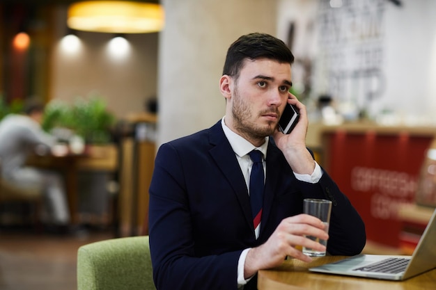 Foto empresario pensativo serio hablando por teléfono