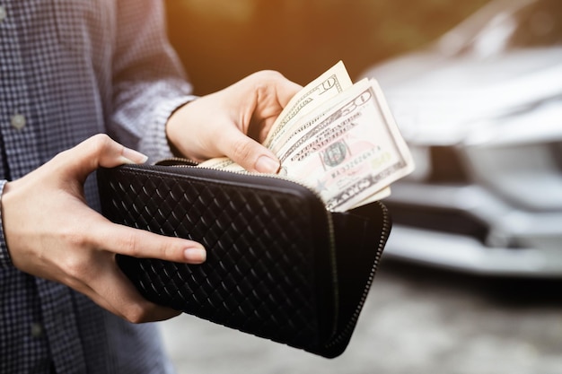 Empresario Persona que sostiene una billetera en las manos de sacar dinero del bolsillo frente al coche preparar el pago a plazos - seguro, préstamo y compra de seguro de concepto de financiación de coche, pago de un coche