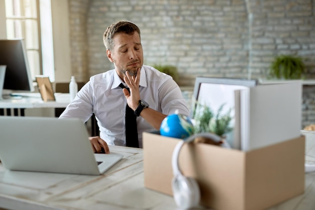 Empresário perturbado usando computador e se sentindo triste depois de ser demitido do trabalho