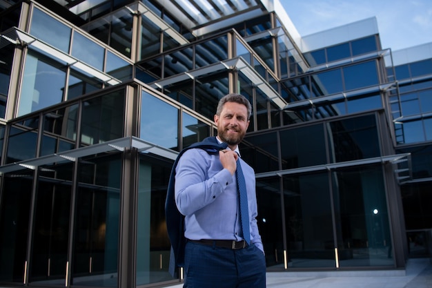 El empresario de pie en la ciudad está feliz de tener éxito en su trabajo ganador del hombre de negocios