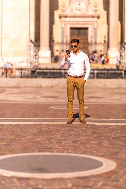 Un empresario en una plaza usando su teléfono inteligente