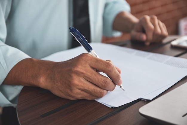 Empresario con pluma y escribir en papeles