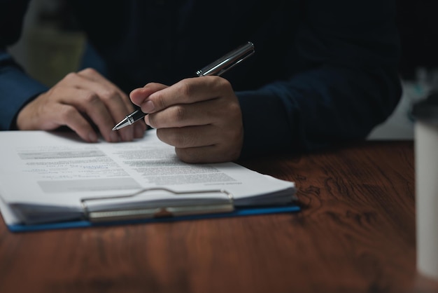 Empresario con una pluma firmando un documento de contrato en el escritorio