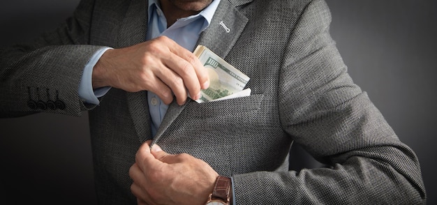 Empresario poniendo billetes de dólar en el bolsillo