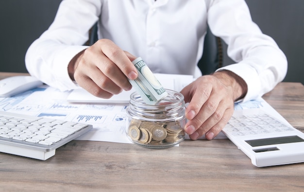 Empresario poniendo dinero en banco de cristal. Ahorrando dinero