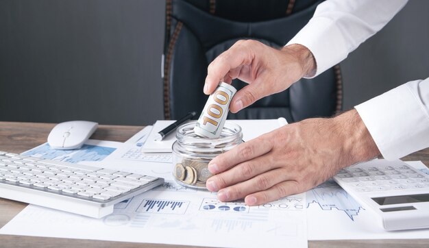 Foto empresario poniendo dinero en banco de cristal. ahorrando dinero