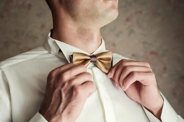 Empresario poniéndose corbata de moño, tendedero de mariposas, preparándose en la mañana antes de la ceremonia de boda